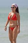 Chubby mature woman in red bikini and sunglasses at the beach
