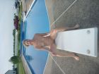 Nudist_woman_sitting_on_diving_board_of_backyard_pool